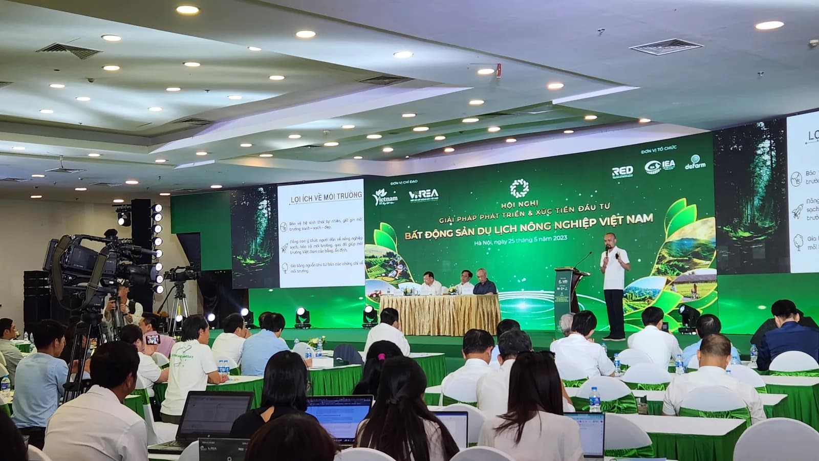 Toàn cảnh hội trường Hội nghị Bất động sản Du lịch Nông nghiệp Việt Nam ngày 25/05/2023 với đại biểu kín chỗ, máy quay truyền hình tác nghiệp phía trái